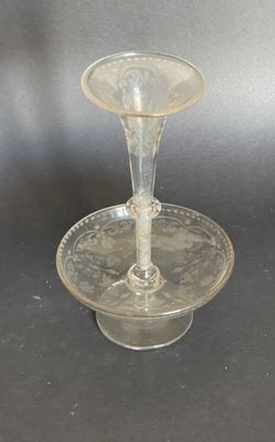 un plat à gâteau en verre sur lequel est posé un bougeoir en verre