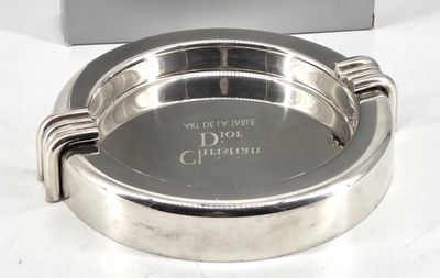 a silver ashtray on a white table with a box in the background