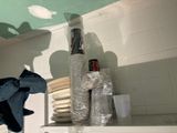 a stack of plates and cups on a shelf in a kitchen