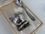 a silver cup and spoon in a box with a spoon and spoon rest