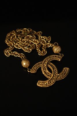 a close up of a gold necklace with pearls on a black background