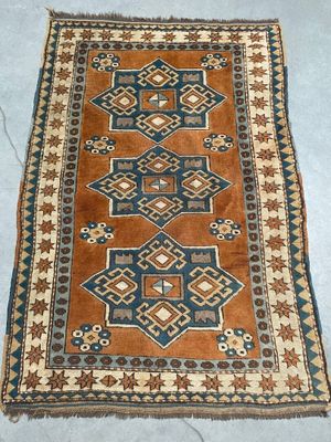 a brown and blue rug on a blue floor next to a white wall
