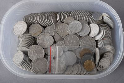 un récipient en plastique rempli d'une multitude de pièces de monnaie posé sur une table