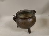 a small bronze pot sitting on a stand on a table