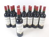 six bottles of red wine lined up in a row on a white surface