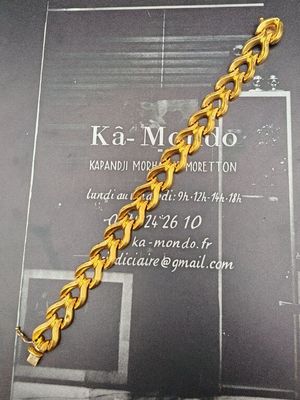 une photo d'un bracelet en or exposé devant une carte de visite