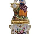 a figurine of a woman sitting on top of a cow