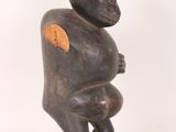 statue of a monkey holding a piece of wood in its right hand
