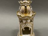 a white and gold vase with a bird on it