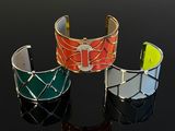 three different colored cuff bracelets on a black surface