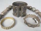 a silver bracelet, bracelets, and a ring on a table