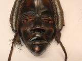 un vieux masque en bois avec des dreadlocks sur fond blanc