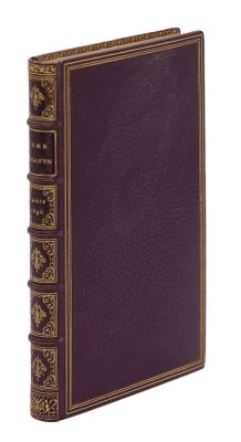 un vieux livre à la couverture violette posé sur une surface blanche