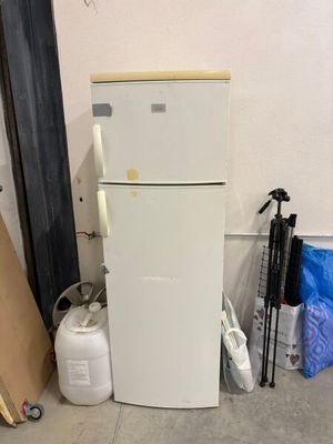 a white refrigerator in the corner of a room next to a wall