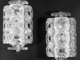 two glass sconces on a black surface with a black background