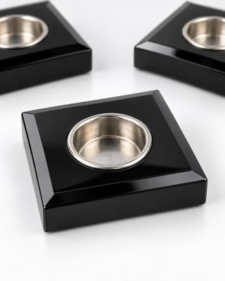 three black square shaped dishes with a metal bowl in the middle of them