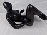 une statue noire représentant une femme allongée sur un drap blanc