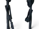 pair of black sculptures of a man and a woman holding umbrellas