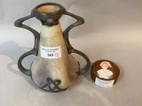 a small vase with a tag on it next to a small bowl