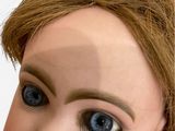 a close up of a doll ' s face with blue eyes