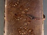 un vieux livre relié en cuir avec un motif floral sur la couverture