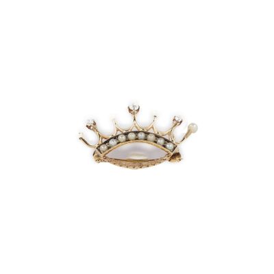 un gros plan d'une broche en forme de couronne ornée de perles, sur fond blanc
