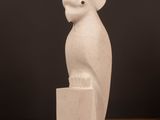 une sculpture blanche représentant un oiseau perché sur une table en bois