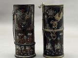 une paire de vases noirs et dorés posés sur une surface blanche
