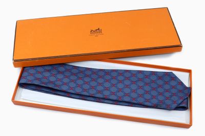 une cravate orange et bleue dans un coffret cadeau, posée sur un fond blanc