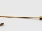 a gold pin with a key on it on a white surface