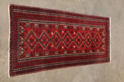 un vieux tapis rouge et noir accroché au mur