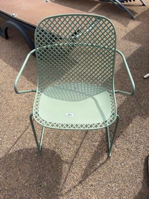 a green chair sitting on the ground next to a table and chairs