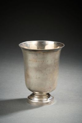 une coupe ancienne en argent posée sur un socle, sur une surface grise