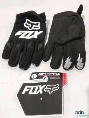 des gants et des autocollants Fox Racing posés sur une table, à côté d'un téléphone
