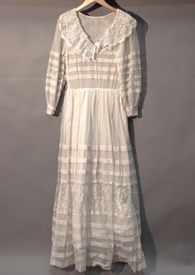 une robe blanche suspendue à un cintre devant un mur gris
