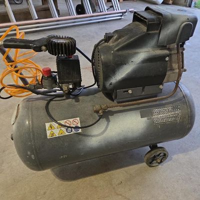 un petit compresseur d'air posé par terre dans un garage