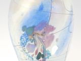 un vase en verre avec un tableau posé sur une table