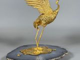 une image représentant une statue de grue en or posée sur une assiette noire et blanche