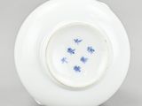 a white vase with blue flowers on it sitting on top of a table