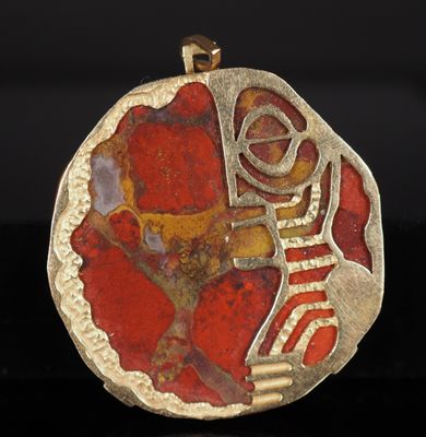 un gros plan d'un pendentif rouge et doré sur une surface noire