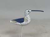 a small metal bird that is standing on a blue stand