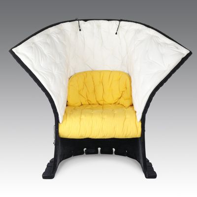 une chaise noire et blanche sur laquelle est posé un coussin jaune