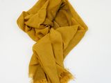 yellow scarf with fringes on a white surface