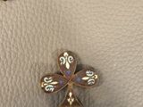 a close up of a small cross on a white leather surface
