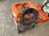 a small orange machine with a hose on the floor