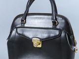 sac à main en cuir noir avec des finitions dorées sur fond gris