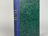 un livre bleu et vert posé sur une table blanche