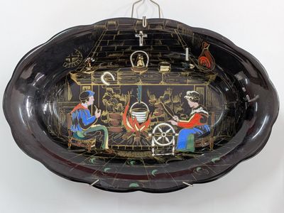 a black bowl with a painting on it hanging on a wall