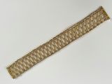 gros plan d'un bracelet en chaîne en or sur une surface blanche