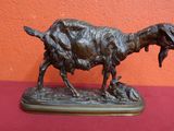 statue of a goat with a bird in its mouth on a red surface